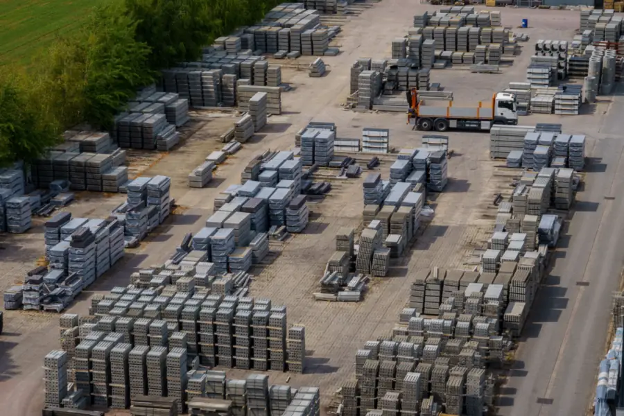 Luchtfoto van een opslagterrein vol pallets met betonstenen, ter illustratie van materiaalkosten voor een oprit in Amsterdam