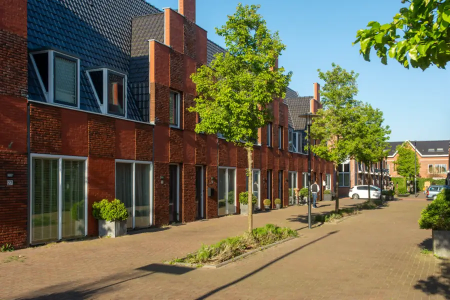 Rij bakstenen eengezinswoningen met een geklinkerde straat en bomen, typisch voor straten waar parkeren op eigen erf geregeld is
