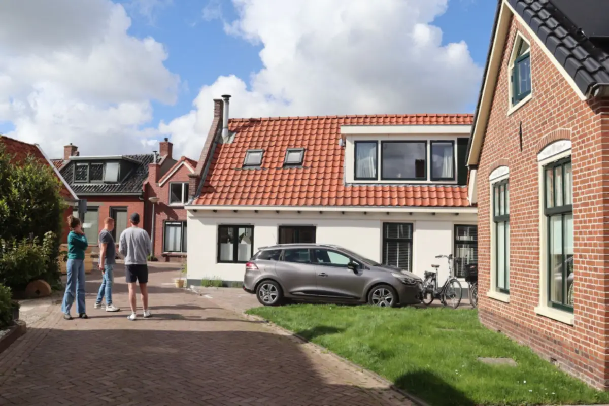 Oprit van gebakken klinkers in visgraatverband tussen twee Nederlandse woningen, voorbeeld van een oprit aanleggen in Amsterdam